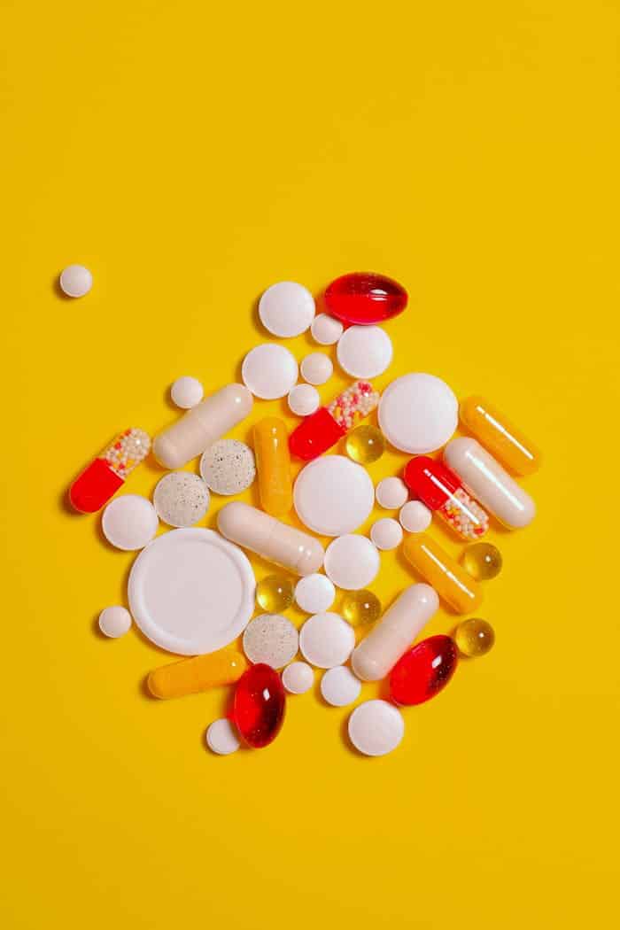A collection of diverse tablets and capsules on a vibrant yellow background, symbolizing healthcare and medication.